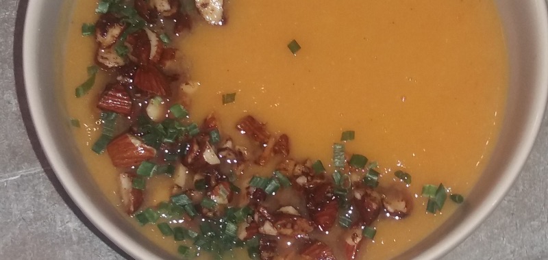 Soep van zoete aardappel (bataat) - met topping van geroosterde notenstukjes en groene kruiden